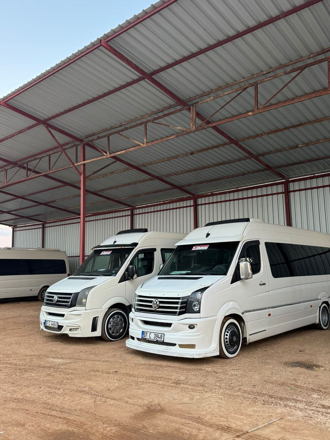 Sundurma altında bekleyen beyaz minibüsler
